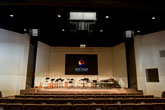 Stage view showing projector screen and musical instruments with microphones and amplifiers integrated by HIFi Doc